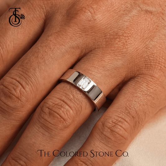 Silver men's wedding ring with a diamond on a person's finger, branded 'The Colored Stone Co'.