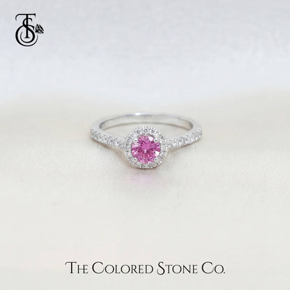 white gold engagement ring with a pink sapphire gemstone on a light background, branded 'The Colored Stone Co'.