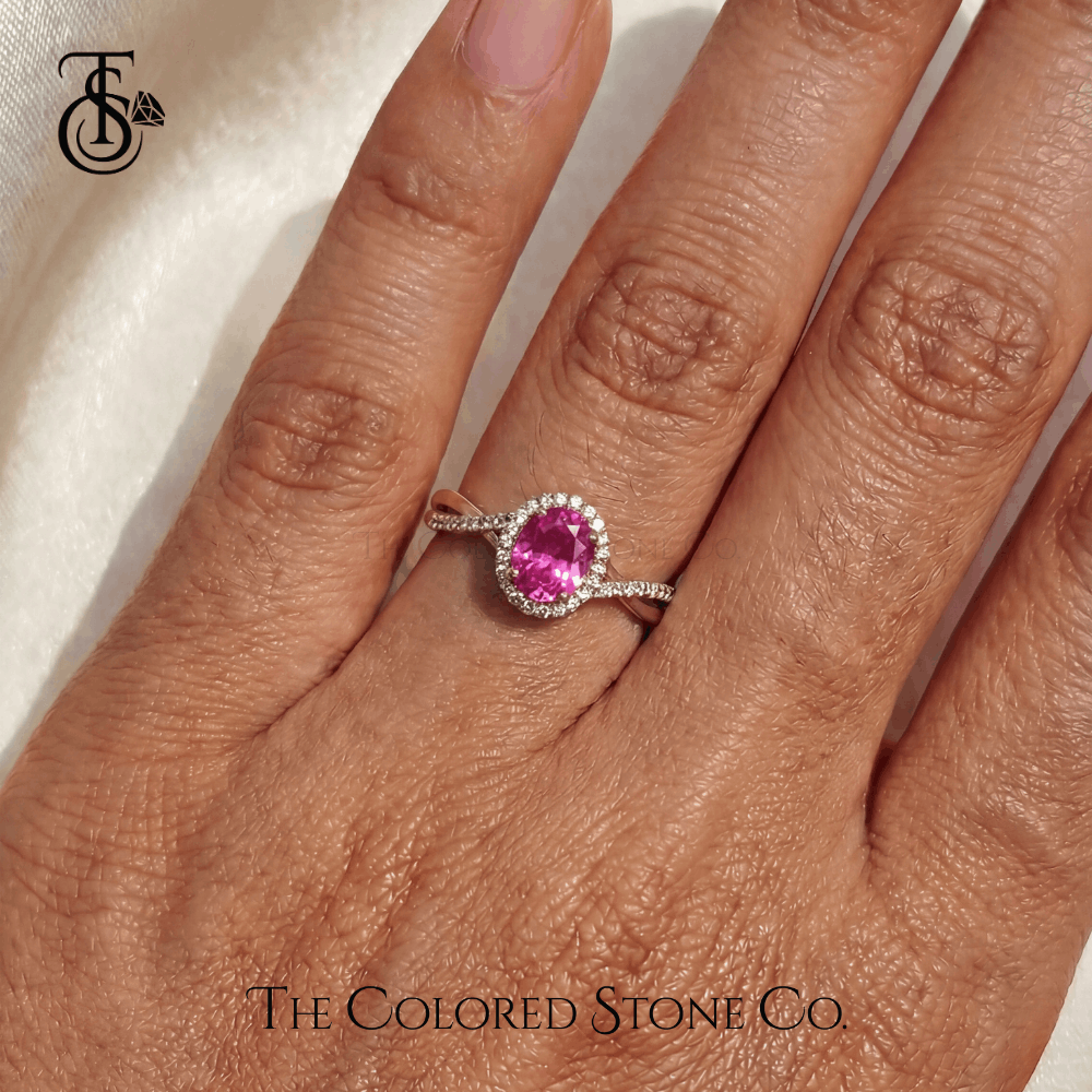Engagement Ring with a pink sapphire gemstone on a hand, branded 'The Colored Stone Co'.