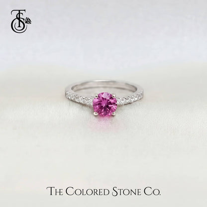 white gold engagement ring with a pink sapphire gemstone on a light gray background, featuring 'The Colored Stone Co.' branding.