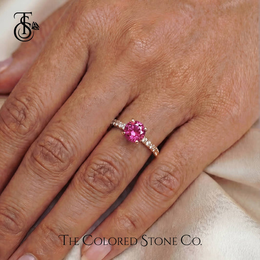Pink gemstone ring on a hand with 'The Colored Stone Co.' branding.
