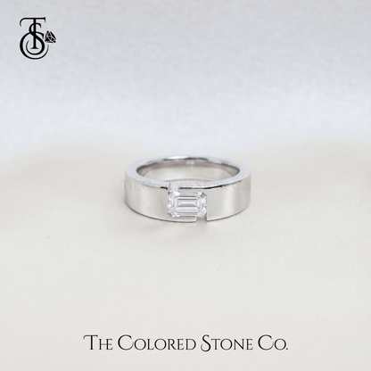Silver men's wedding ring with a rectangular diamond on a light gray background, featuring 'The Colored Stone Co.' branding.
