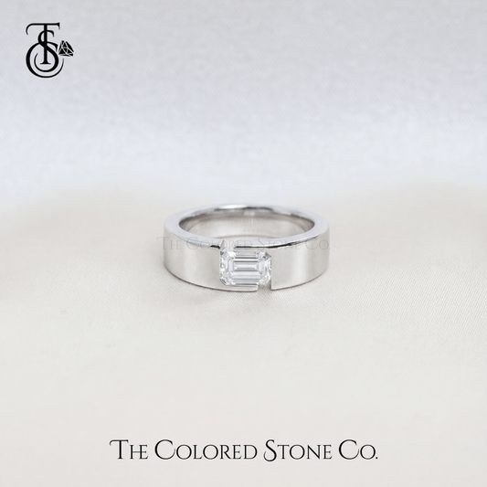 Silver men's wedding ring with a rectangular diamond on a light gray background, featuring 'The Colored Stone Co.' branding.
