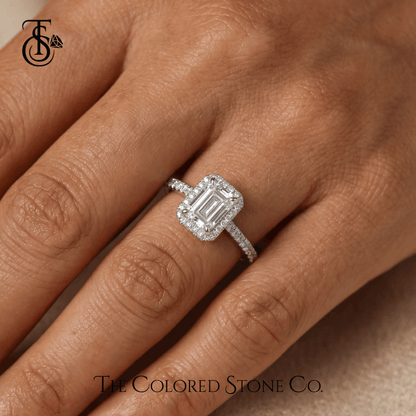 Diamond engagement ring on a finger with 'The Colored Stone Co.' branding.