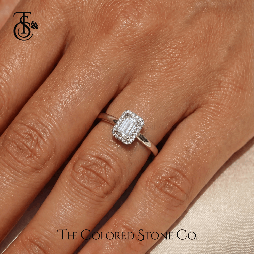Diamond ring on a finger with 'The Colored Stone Co.' branding.