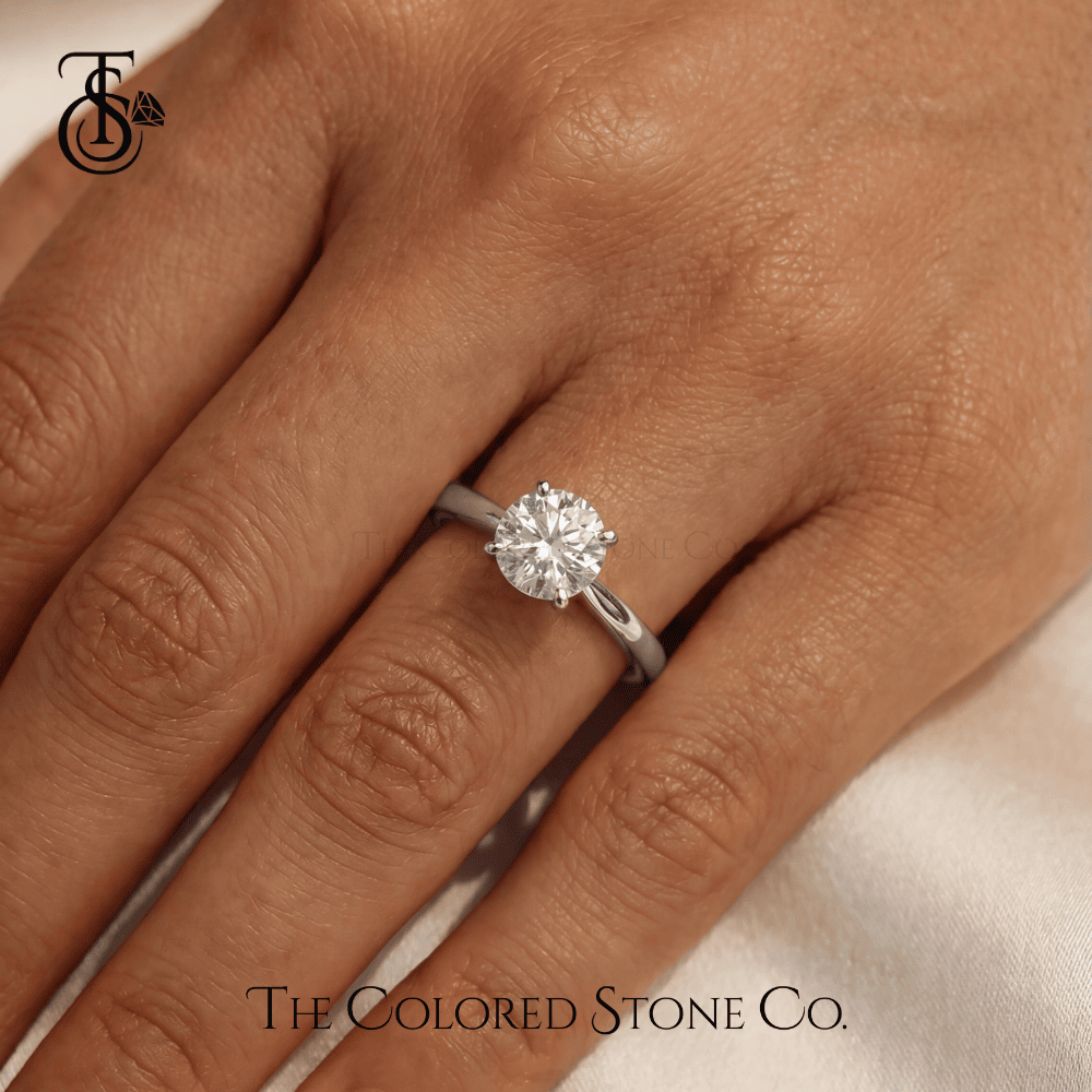 White Gold engagement ring on a hand with 'The Colored Stone Co.' branding.