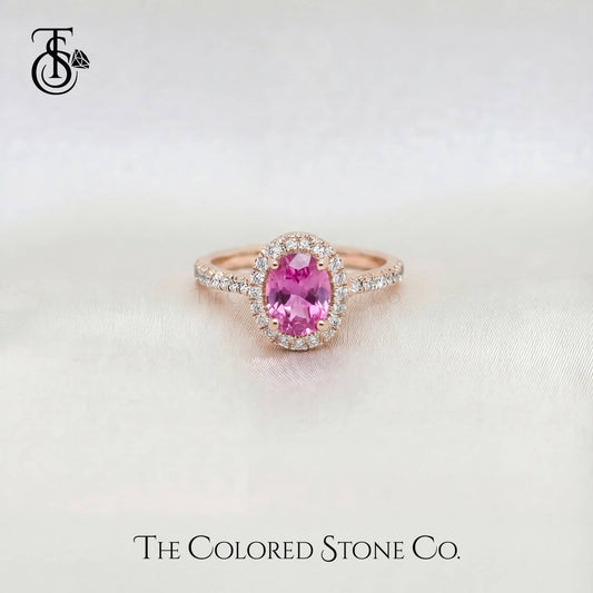 Rose gold pink engagement ring with a pink sapphire gemstone on a light background, featuring 'The Colored Stone Co.' logo.