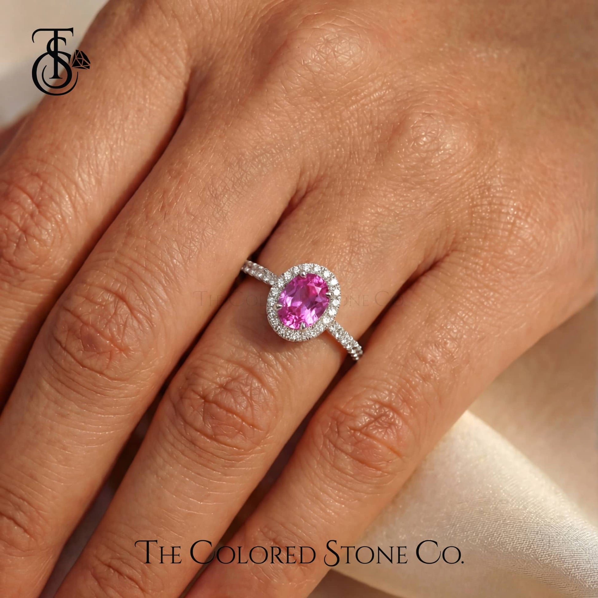 Pink gemstone ring on a hand with 'The Colored Stone Co.' branding.