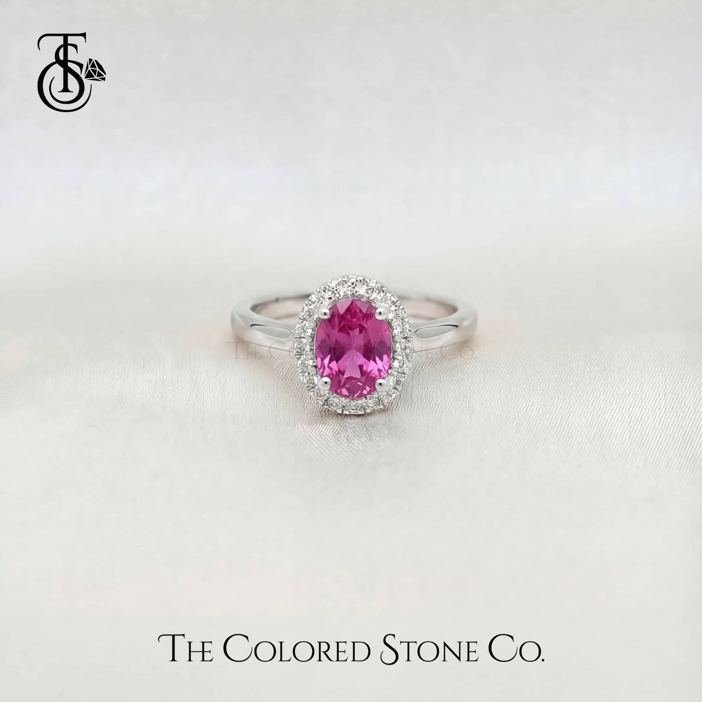 white gold enagement ring with a pink sapphire gemstone on a white background, branded 'The Colored Stone Co'.