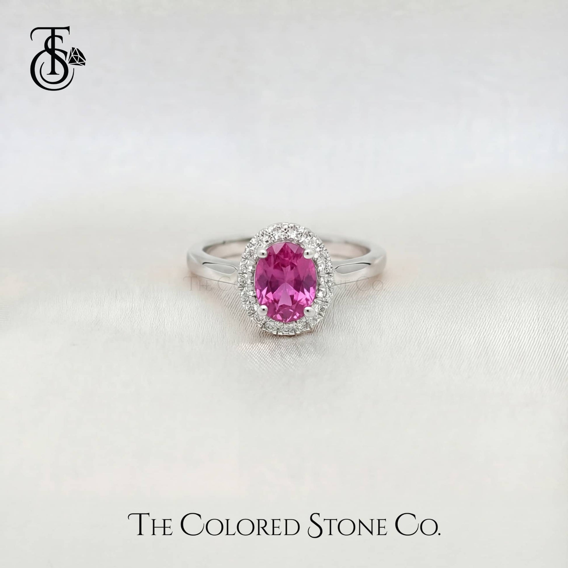 white gold enagement ring with a pink sapphire gemstone on a white background, branded 'The Colored Stone Co'.