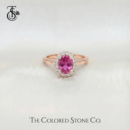 Rose gold engagement ring with a pink sapphire gemstone on a light background, featuring 'The Colored Stone Co.' branding.