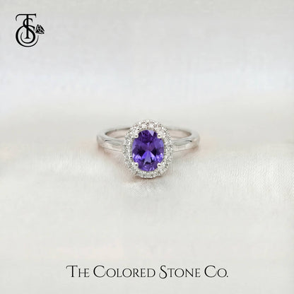 white gold engagement ring with a purple sapphire gemstone on a white background, branded 'The Colored Stone Co'.