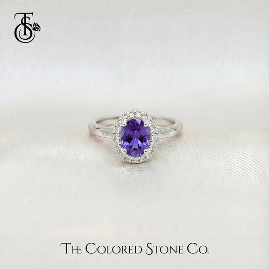 white gold engagement ring with a purple sapphire gemstone on a white background, branded 'The Colored Stone Co'.