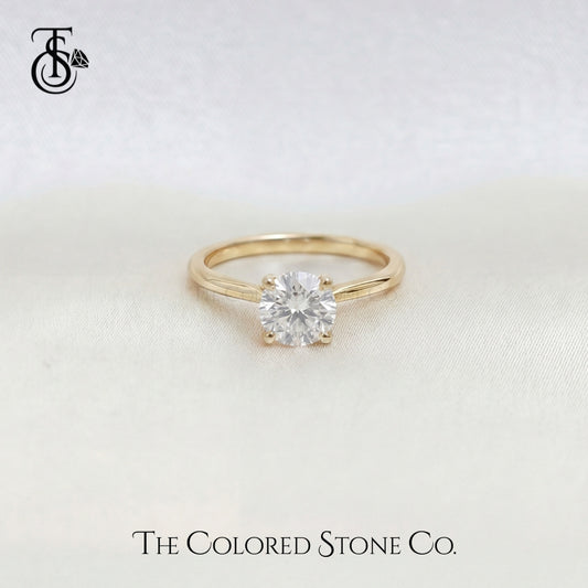Yellow Gold engagement ring with a diamond on a light background, featuring 'The Colored Stone Co.' logo.