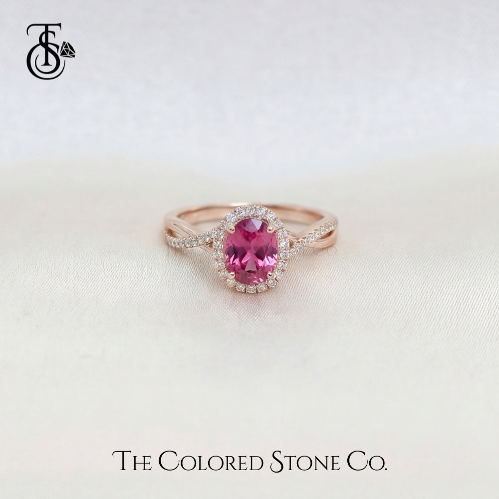 Rose gold engagement ring with a pink sapphire gemstone on a light background, featuring 'The Colored Stone Co.' branding.