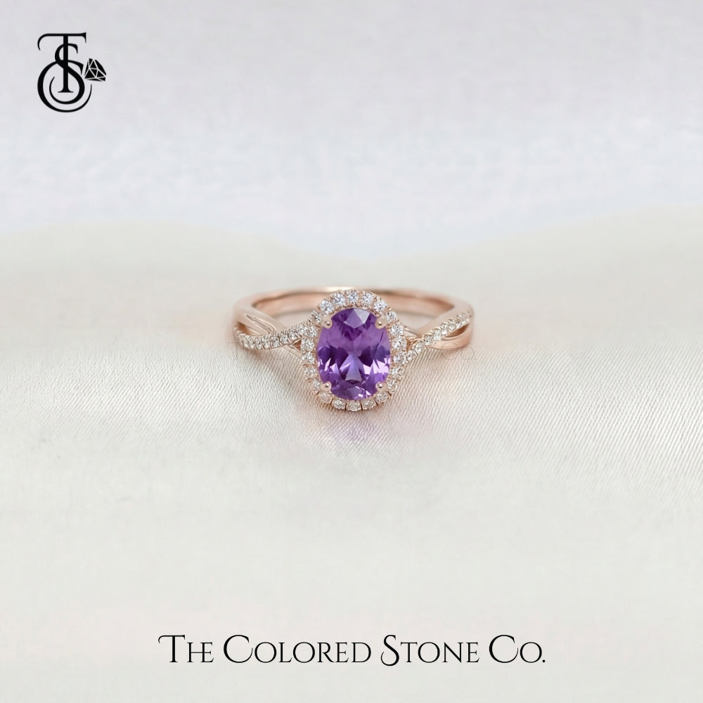 Rose gold engagement ring with a violet sapphire gemstone on a light background, featuring 'The Colored Stone Co.' logo.