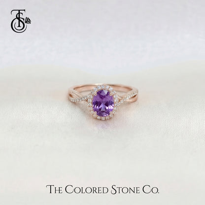 Rose gold engagement ring with a violet sapphire gemstone on a light background, featuring 'The Colored Stone Co.' logo.